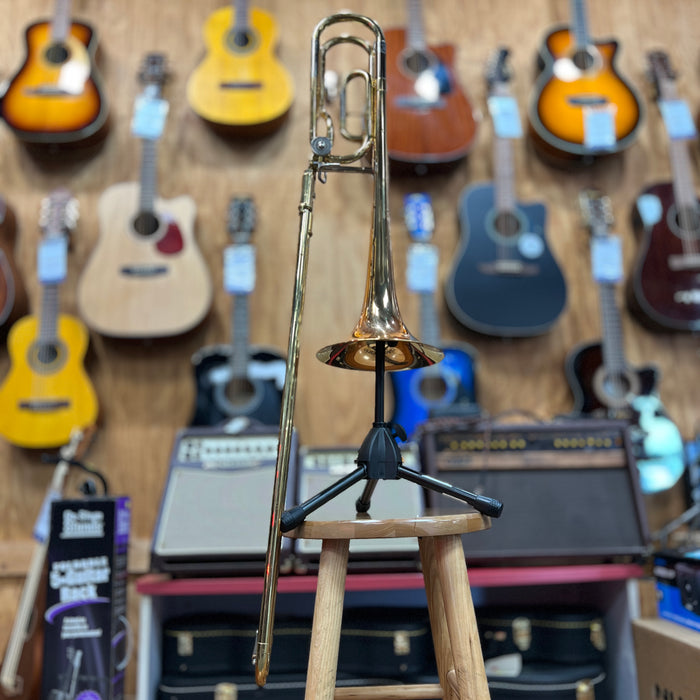 Trombone on a stand with guitars and amplifiers in the background